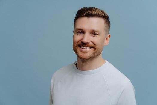 files/handsome-cheerful-bearded-man-smiles-gladfully-dressed-in-casual-white-t-shirt-being-in-good-mood-poses-against-blue-background-with-copy-space-glad-european-guy-with-stubble-stands-i.jpg